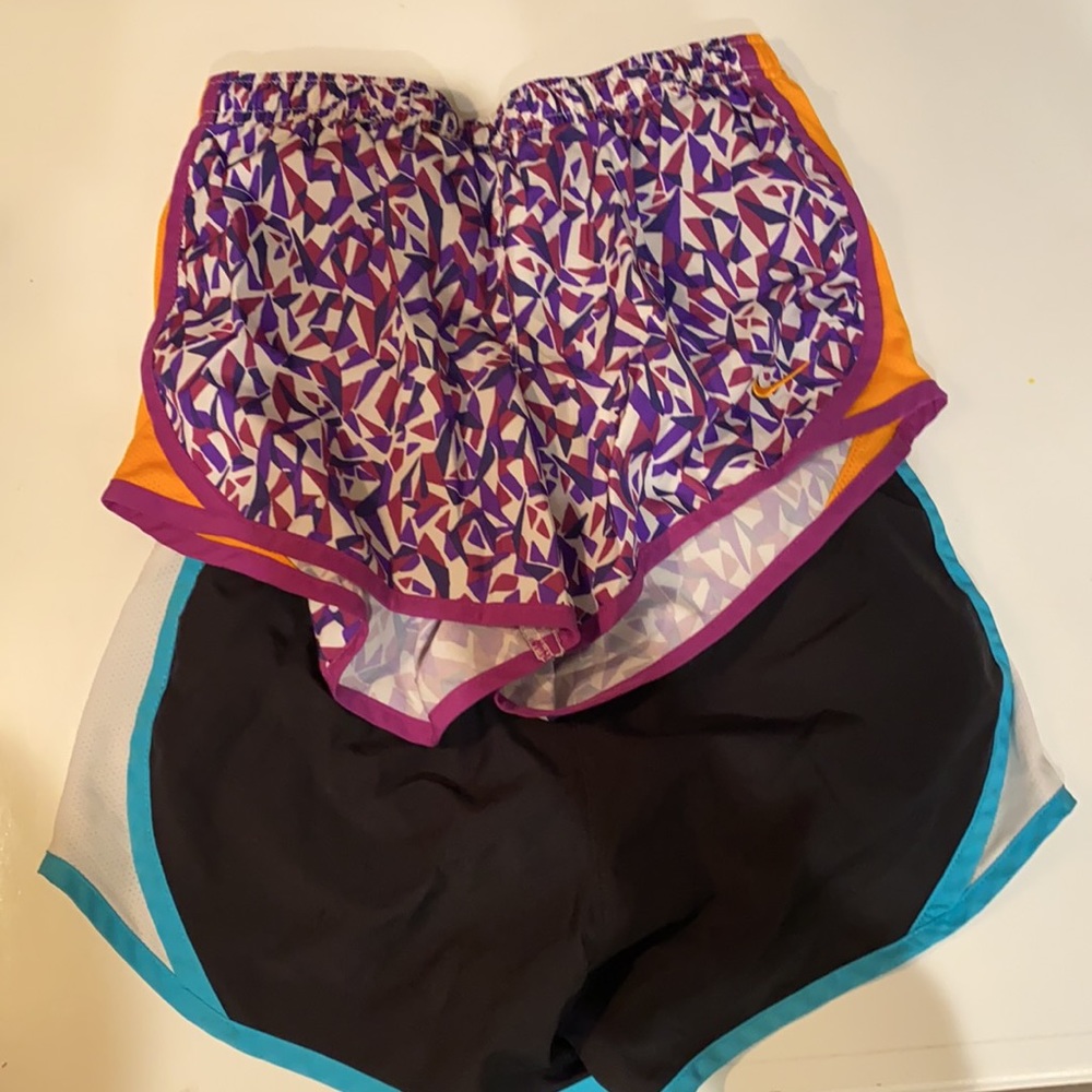 Two Nike youth medium athletic shorts blue and black, & purple and orange.